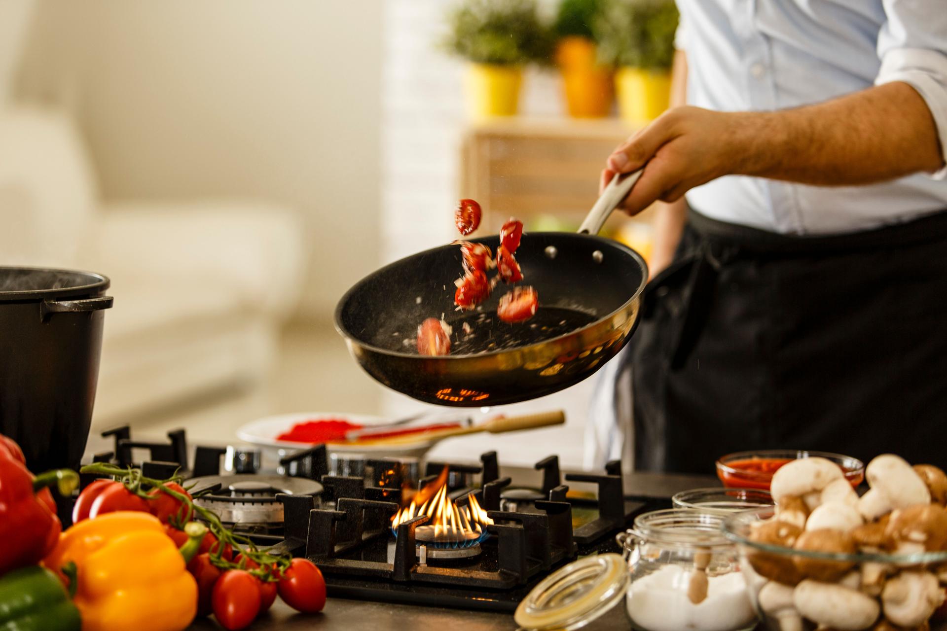 Chef, jogando legumes de cozimento pan